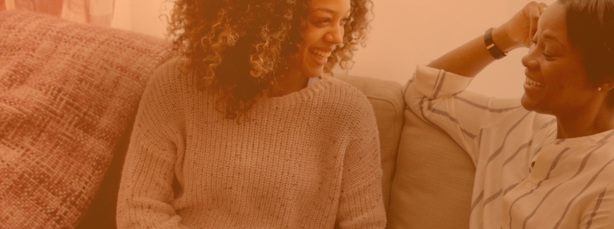 Two women sitting on the couch smiling